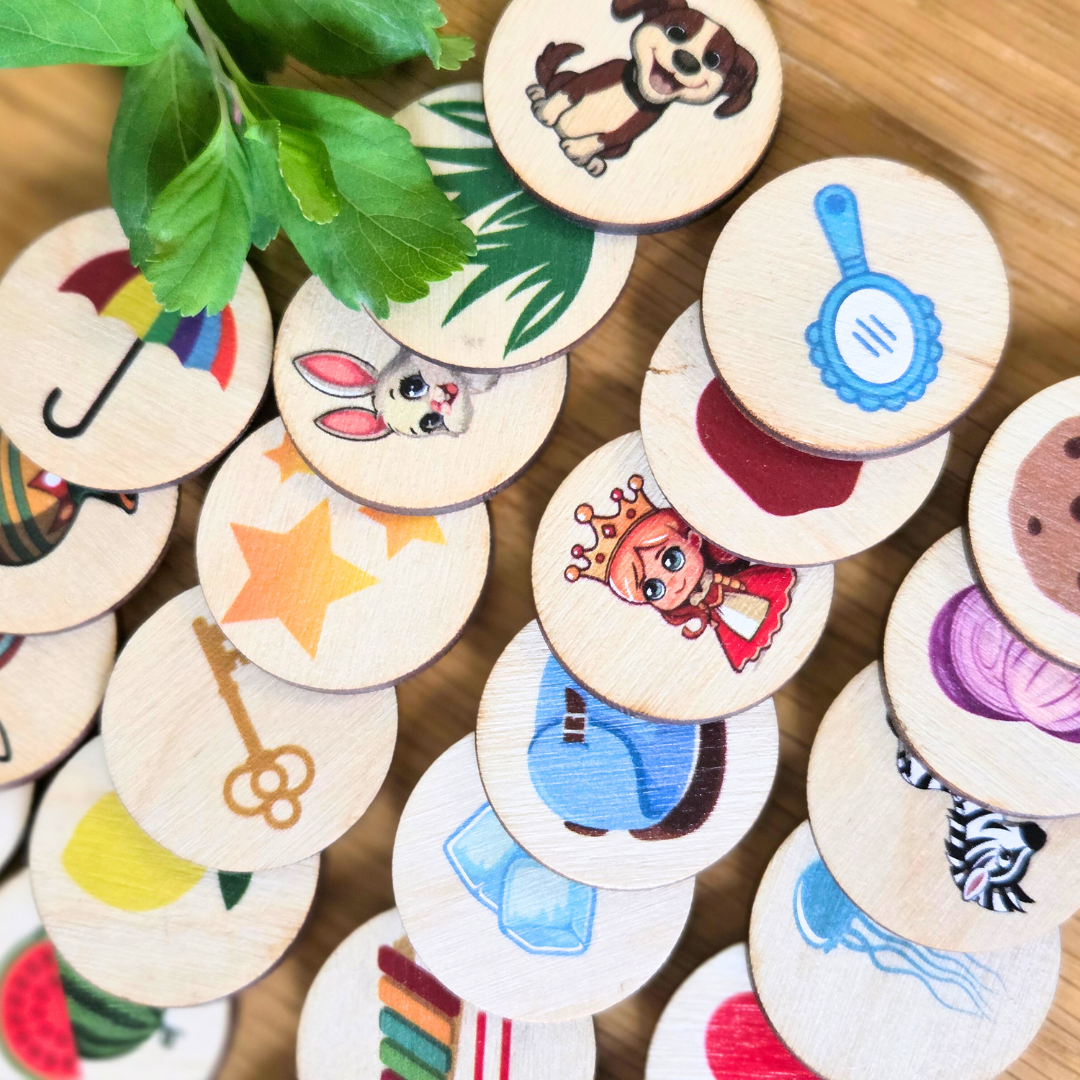 Collection of wooden buttons with various illustrations on a wooden surface for ABC beginning sounds puzzle