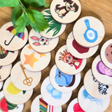 Collection of wooden buttons with various illustrations on a wooden surface for ABC beginning sounds puzzle