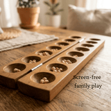 Wooden game board with seeds on a wooden table, text 'Screen-free family play' visible.